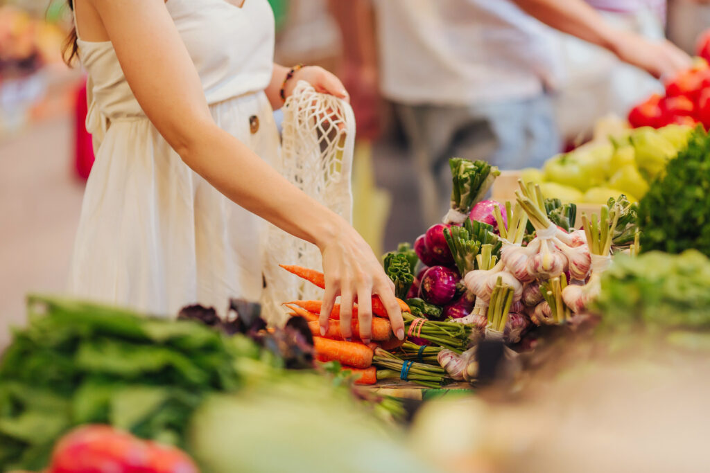 Female hands puts fruits and vegetables in cotton produce bag