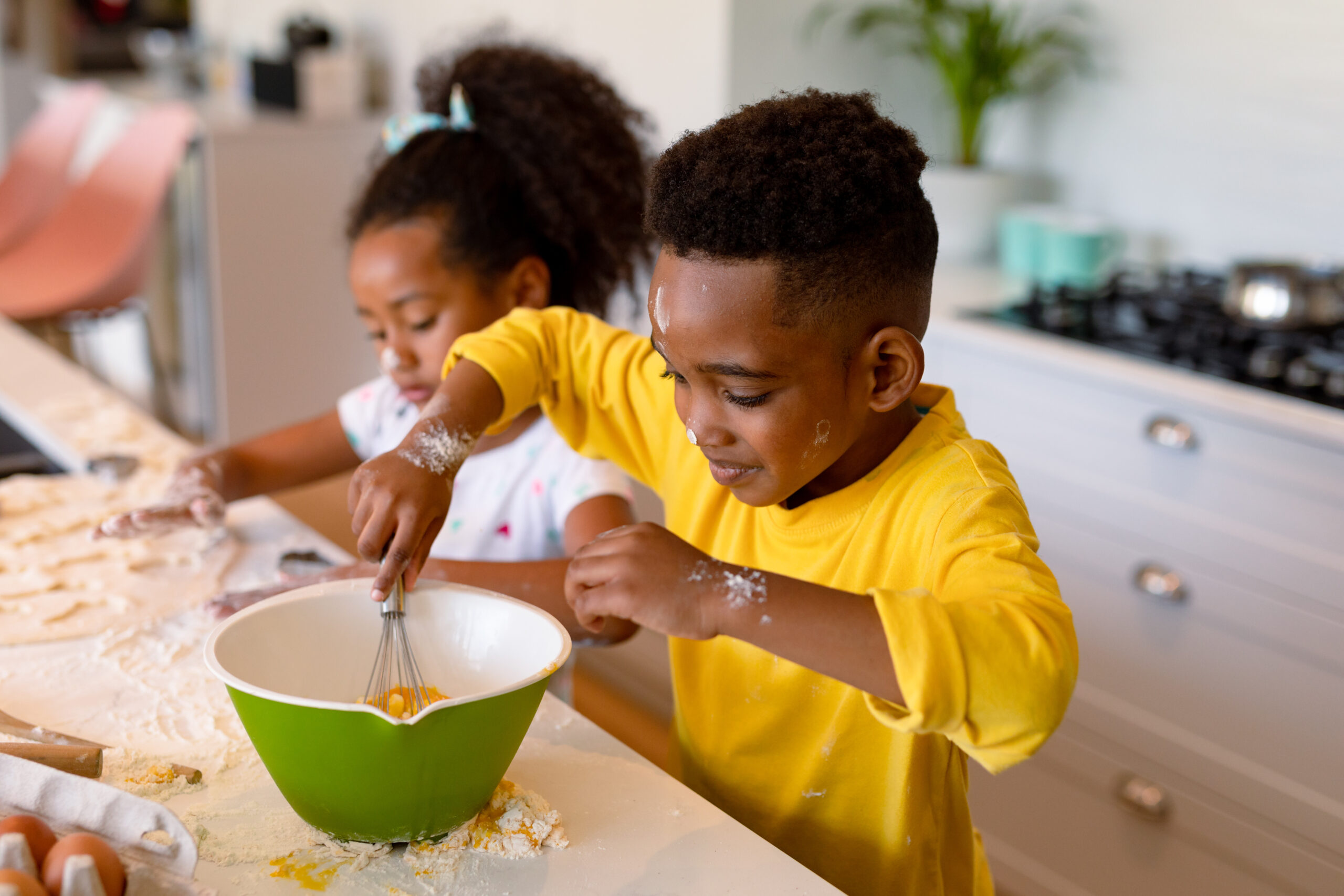 Happy african american siblings baking in kitchen