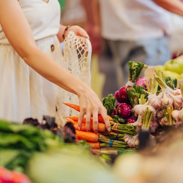 Female hands puts fruits and vegetables in cotton produce bag